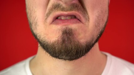 Close-up mouth of angry man screaming. Threat of violence, Emotions of anger. Red Background, Studio Video, 4K, Isolate.