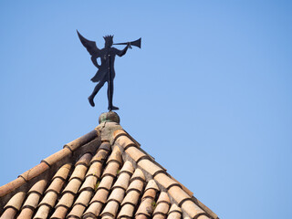 Obraz premium Antique Weather vane on the tile roof over Girona Old City in Spain. Copy Space. Man with trumpet.