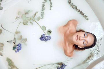 Fototapeta na wymiar girl in a bath with milk and flowers