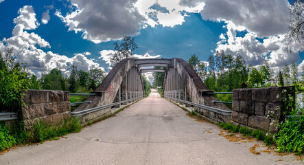 Fototapeta na wymiar Old bridge with cotton white clouds over a blue summer sky 