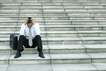 Businessman sitting on the stairs with his hands on the head