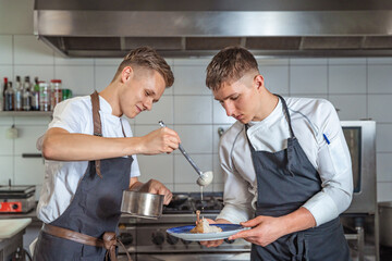 preparing meat with sauce by two young chefs
