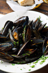 Mussels. Classic French or American restaurant appetizer: steamed mussels. Shellfish steamed with white wine, butter, garlic, onions and fresh herbs. Served with butter toasted baguettes.