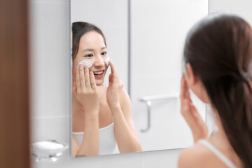 Obraz na płótnie Canvas Woman happy cleanses the skin with foam in bathroom.
