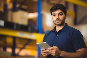 Man warehouse worker using tablet to check and control with modern trade warehouse logistics business, holding digital tablet standing in aisle with goods