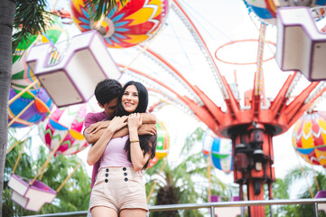 Obraz na płótnie Canvas romantic lover couple embracing hug at amusement park, dating at theme park
