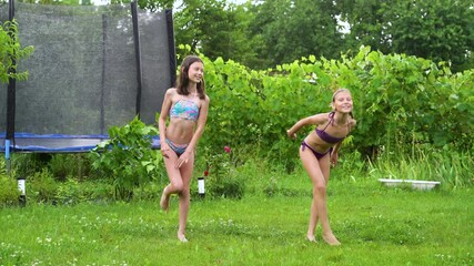 Happy children in swimwear dancing under rain in backyard