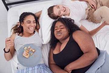 Diverse young females kidding and joking while lying on bed