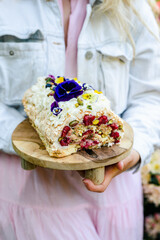 Women's hands holding a tray with a delicious meringue dessert.