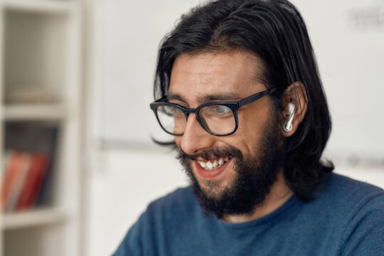 Close up portrait of happy man wearing eyeglasses teaching online, looking at web camera and smiling. Male teacher working from home