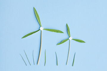 two windmills made of fresh green leaves on blue, eco wind renewable energy, green power
