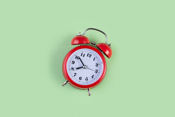 Red vintage alarm clock on light green color background. Alarm clock with place for text. Time...