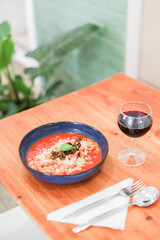 A served table with pasta and wine, tomato fusilli pasta with a glass of red wine on a wooden table
