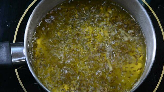 Preparing Cumin tea. Boiling water, cumin seeds and ginger.