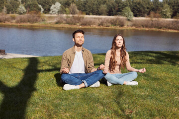 Pretty young woman meditating with her boyfriend outdoors