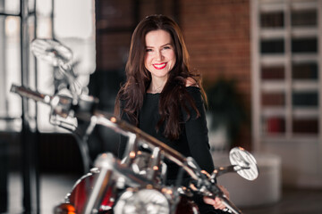 Fototapeta na wymiar Portrait Of Smiling Woman Sitting On Motorcycle Against Building