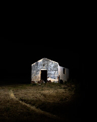 White washed farm building illuminated by a single light at night