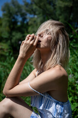 portrait of a girl with light hair in nature. Blonde face hair style. Close his eyes. Sunlight.