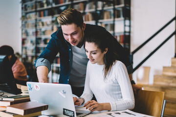 Skilled male and female students making research together in networks learning in colleague campus with wifi,smiling colleagues satisfied with cooperation on project watching webinar online