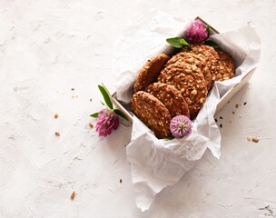 A box of oatmeal cookies and clover flowers on a light background with space for text. Top view