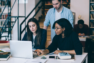 Group of smart students at table with laptop