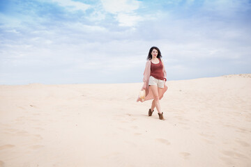 Fototapeta na wymiar girl in desert walk with dark hair shorts, sand and blu sky background