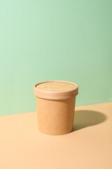 Craft paper soup cup on green and brown natural color paper. Container. Delivery food. Ecological individual package. Zero Waste.