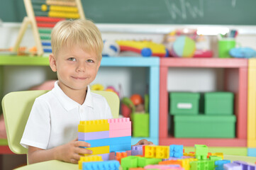 Fototapeta premium Portrait of boy playing with colorful plastic blocks