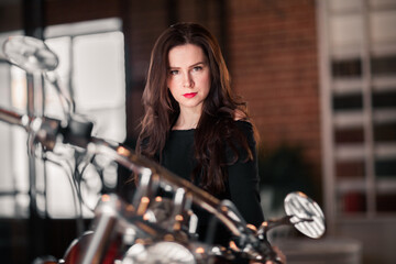 Fototapeta na wymiar Portrait Of Confident Woman Sitting On Motorcycle Against Building