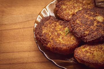 Potato patties fried lie in brown utensils on a wooden board