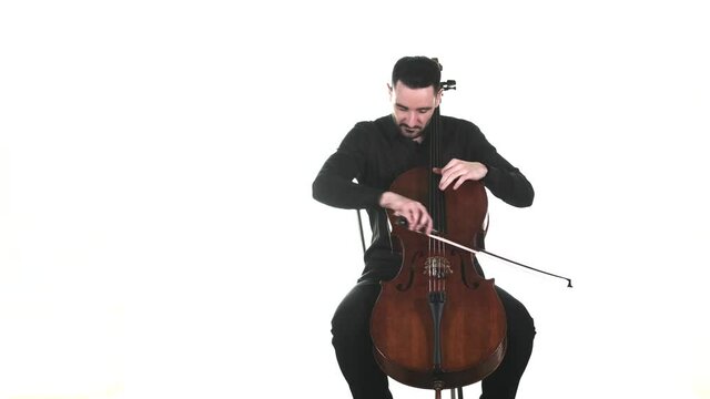 masterly musician in a black shirt performs a beautiful slow melody on a classical cello. Isolated. Medium long shot