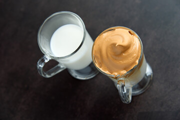 Glasses of trendy fluffy creamy dalgona or whipped instant coffee with milk on the dark background. New popular food and drink trend concept. Copy space.