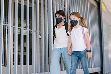 Two sisters entering school at the beginning of the year with masks on their faces