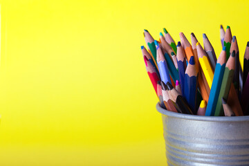 bucket with pencils on a yellow background