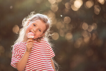 Portrait of a little girl with wavy blond hair, eating ice cream, enjoying the setting sun