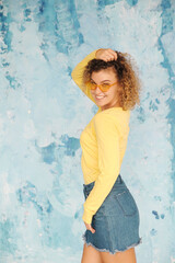 Stylish smiling woman in yellow clothes posing on background. 