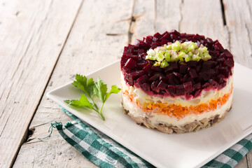 Traditional Russian herring salad with beetroot and carrots on wooden table	