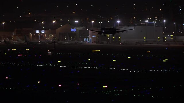 Airplane landing at night at Dubai international airport. helicopter zoom in detail to out revealing airport, 6-axis stabilized gimbal, Shotover F1, 8K, zoom in and out, parallax,