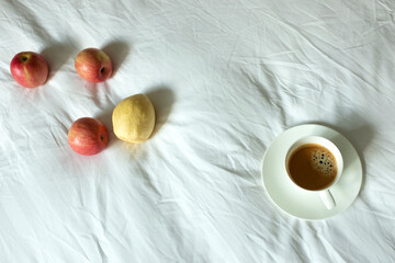 Obraz na płótnie Canvas coffee and fruits on white bed sheet