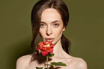 Beauty face of young woman with flower. Beauty treatment concept. Portrait of young woman with rose on green background.