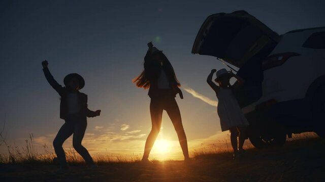 happy family kid dance picnic are jumping dancing dream holiday concept. happy family jump three girls teenagers are standing at sunset next to the car stopped at a picnic. open car trunk lifestyle