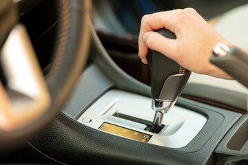 Close up of woman driver holding her hand on automatic gear shift stick driving as car.