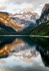 Sunny sunset colorful summer alpine view. Peaceful mountain lake with clear transparent water and reflections. Gosauseen or Vorderer Gosausee lake Salzkammergut Upper Austria. Dachstein summit glacier