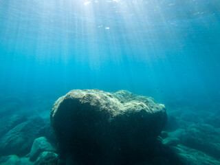 the sun's rays fall from above, penetrating seawater to the bottom. giant stone at the bottom of the sea