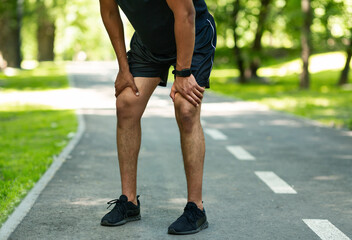 Unrecognizable millennial jogger resting during his morning run at summer park, closeup
