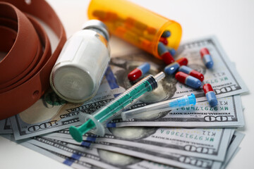 Close up of syringe with injection vaccine, pills and money. Buying or selling illegal substances and drugs