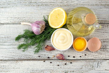Obraz na płótnie Canvas Mayonnaise sauce with garlic, egg, oil, lemon and herbs on wooden background