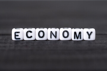 Fototapeta na wymiar Economy word written on white cubes on black background.