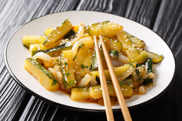 Summer zucchini appetizer with onions, parsley and sesame seeds in soy sauce close-up in a plate on the table. horizontal