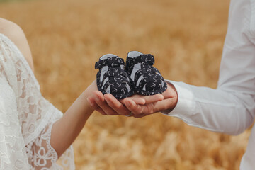 hand holding baby shoes in a wheat field